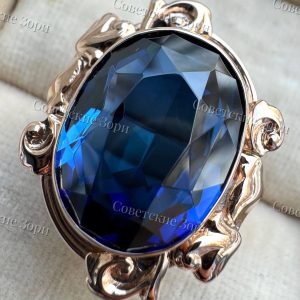 Кольцо «Зеркало Екатерины» с роскошным корундом сапфира глубокого васильково-синего цвета, чья огранка придаёт камню эффект зеркальной глубины. Золото оправы обвивает камень, словно старинное зеркало в золотой раме, сохранившее облик великой эпохи.