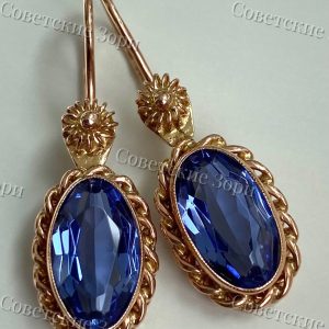 Изысканные серьги времён СССР украшены овальными корундами чарующего голубовато-синего оттенка. Камни играют мягкими переливами — от небесно-голубого до глубокого синего.Ажурная витая оправа придаёт украшению утончённость и подчёркивает сияние каждого камня.